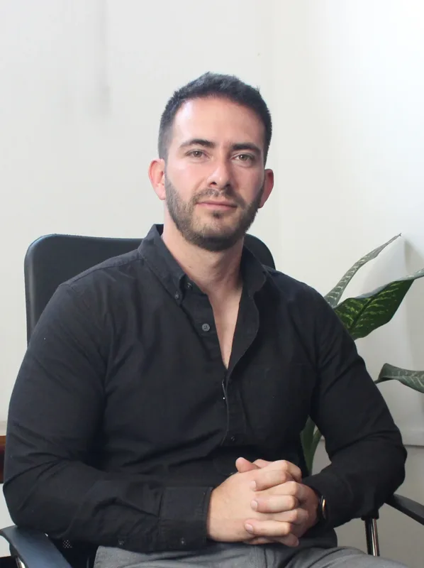 Christian Rodolfo Saldaña Zenteno, arquitecto de Arquitectos Puebla, sentado en su oficina con camisa negra