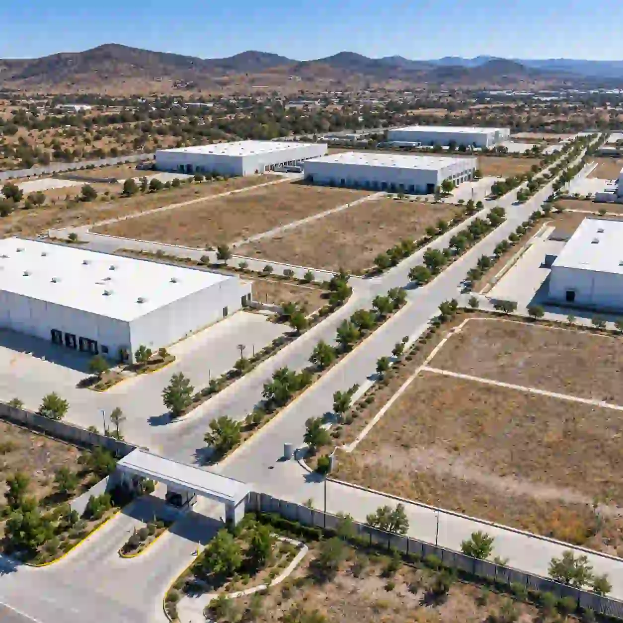 Render aéreo de la lotificación de un parque industrial con naves blancas, lotes delimitados, vialidad con camellón arbolado, patios de maniobra y lomeríos al fondo, en Silao, Guanajuato